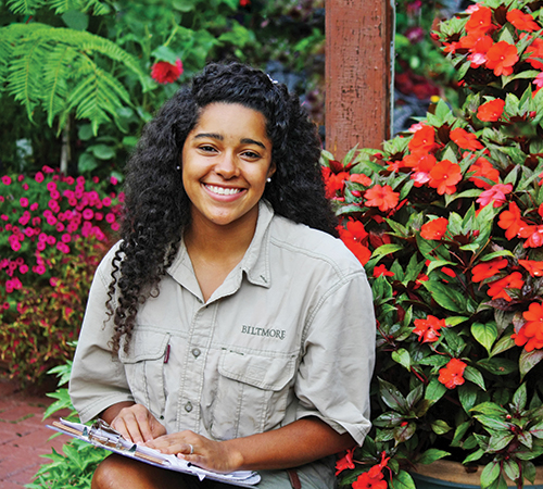 Molly Anne Dutton sitting in front of colorful flowers at the Biltmore Estate.