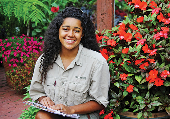 Molly Anne Dutton sitting in front of colorful flowers at the Biltmore Estate.