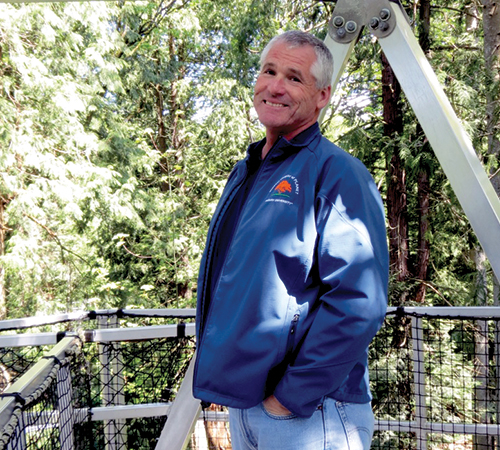 Joe Eakes standing on a bridge in the trees.