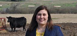 Christy Bratcher standing in a cow pasture.