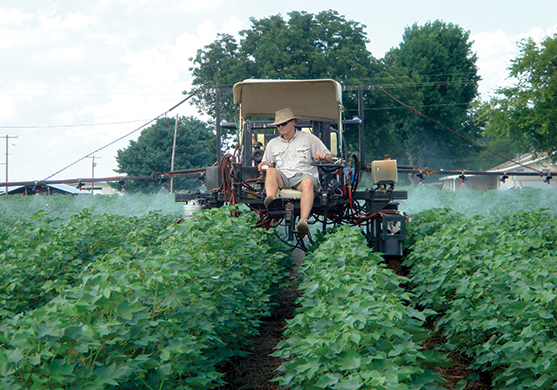 man riding on a machine spraying crop 