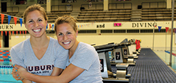 Twin sisters hugging in front of Auburn's swimming pool