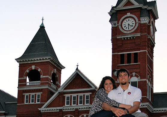 Jordan and Melissa Toombs sitting on top of the Auburn University sign infront of Samford Hall