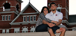 Jordan and Melissa Toombs sitting on top of the Auburn University sign infront of Samford Hall